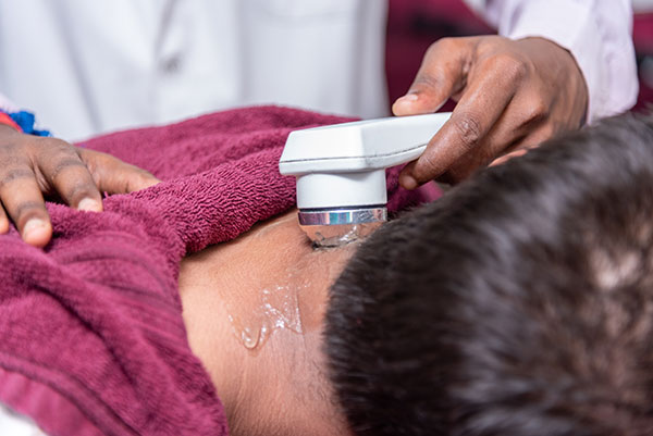 Close-up of therapist applying Patanjali physiotherapy on patient’s shoulder